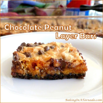 Chocolate Peanut Layer Bars start with chocolate graham cracker crust and are layered with candy bits, dark chocolate chips, peanuts and more. Simple to make, addicting to eat. | Recipe developed by www.BakingInATornad.com | #recipe #bake 