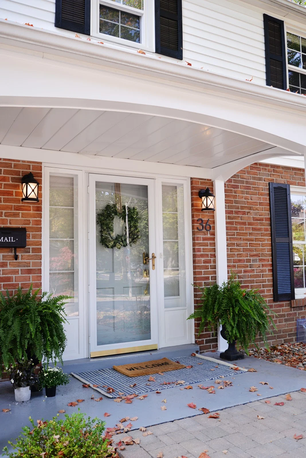 simple fall porch decor with striped rug and heirloom pumpkins