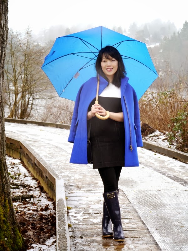 A cobalt blue cocoon coat brightens up a black-and-white colour-blocked sweater dress and navy rain boots.