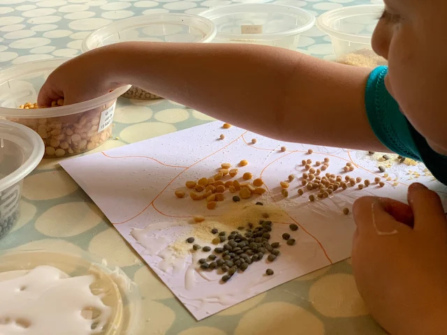 Toddler reaching for more grains to stick on her picture