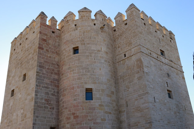 Torre medieval con almenas bien conservada con cielo azul de fondo.
