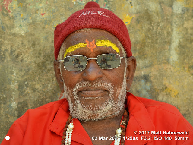 matt hahnewald photography; facing the world; character; head; face; forehead; sandalwood paste; chandanam; tika; tilaka; third eye; urdhva pundra; facial expression; beard; sunglasses; consent; rapport; respect; traveling; religious; traditional; cultural; hinduism; sadhu; devotee; worshiper; pilgrim; dwarka; gujarat; western india; asian; indian; person; male; adult; elderly; man; image; picture; photo; face perception; physiognomy; nikon d3100; nikkor af-s 50mm f/1.8g; prime lens; 50mm lens; nifty fifty; 4x3; horizontal; street; portrait; closeup; head shot; full-face view; outdoor; color; editing; posing; authentic; woolen cap; red