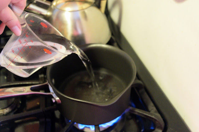 Water being pour into a sauce pot on the stove.