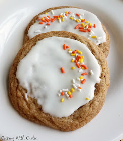 Sink your teeth into a nice chew maple cinnamon cookies. The warm flavors will dance across your taste buds and put on a smile on your face. These cookies are perfect for fall and are great on their own or with a bit of glaze. I'll also show you how to turn them into mummies for Halloween! They are versatile, timeless and delicious! two glazed chewy maple cinnamon cookies with a smattering of sprinkles on them
