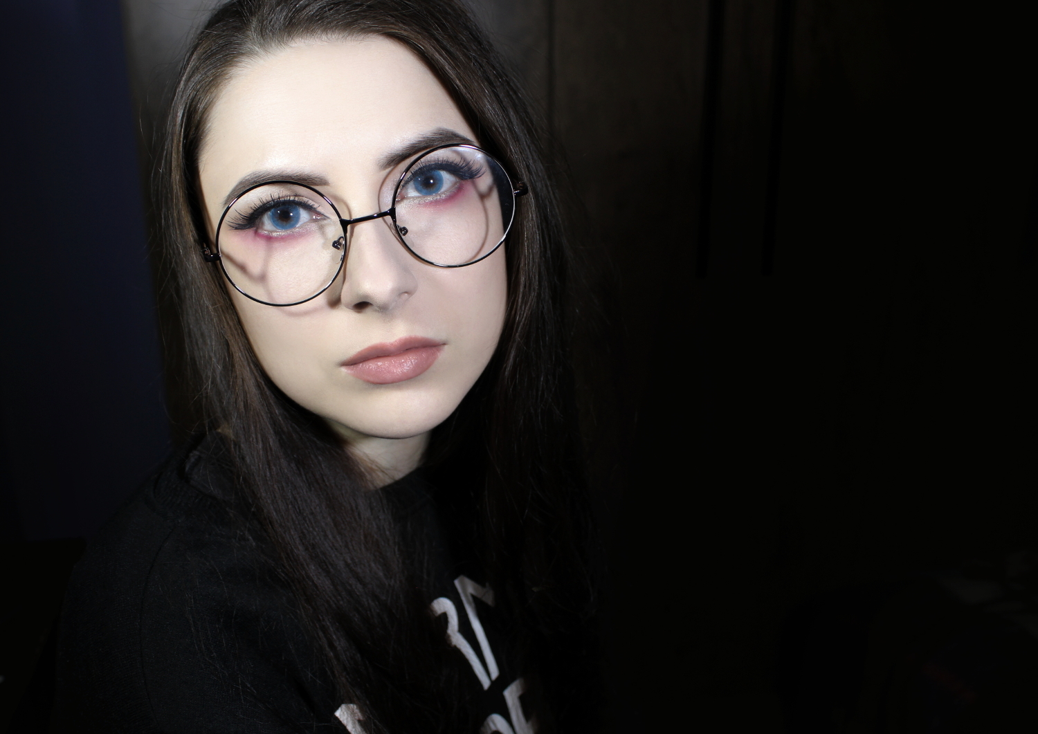 a portrait of a nerd girl in round, vintage-looking eyeglasses and anime makeup look.