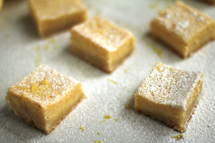 Close up of several lemon brookies topped with powdered sugar and lemon zest.