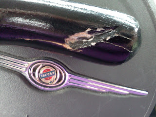The end of a black cane, damaged and cracked, set against the steering wheel of a PT Cruiser