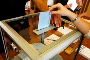 Persona dipositando una papeleta en una urna durante unas elecciones