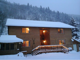 Exterior winter dusk scene with a four-plex, lights shinning from the windows and white lights trim the deck railing.