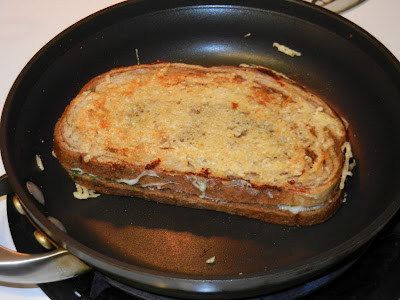 cooked sandwich with parmesan cheese on the top of it in a frying pan 