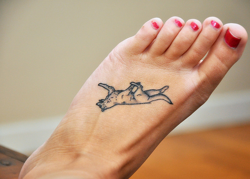 Tatuaje en el pie de una jovencita con las uñas pintadas de rojo