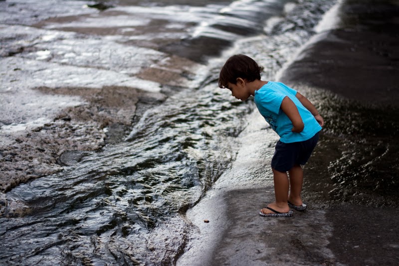 Petit garçon regarde couler l'eau dans un canal