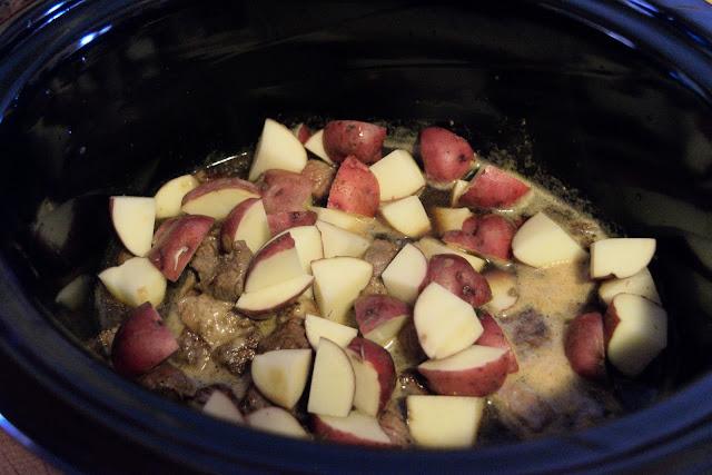 Adding the potatoes to the crock pot. 