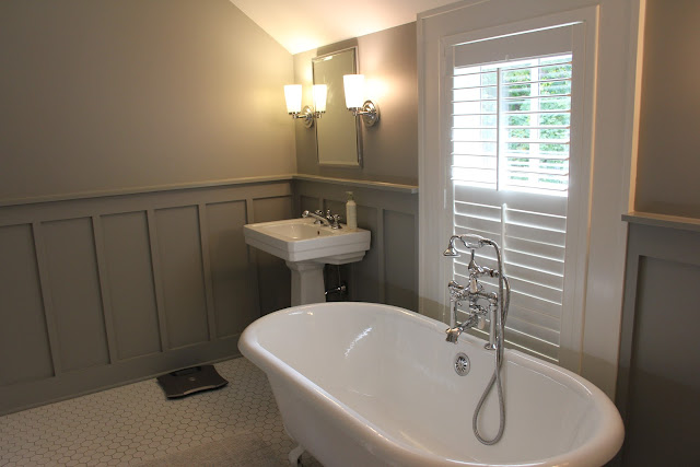 White and grey modern farmhouse bathroom with clawfoot tub and plantation shutters on Hello Lovely Studio