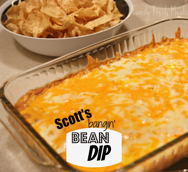 cheesy bean dip in a glass baking dish, with a bowl of tortilla chips