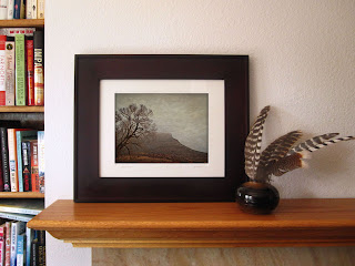 Landscape photography, done in an Old West style, of a foggy mountain landscape with a bare tree and red mesa.