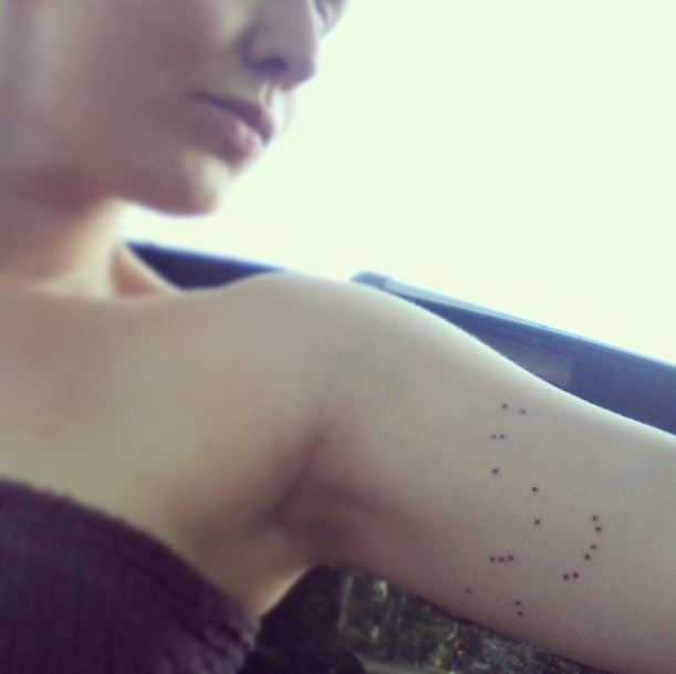 chica con tatuaje de la constelación de orion en el biceps interno