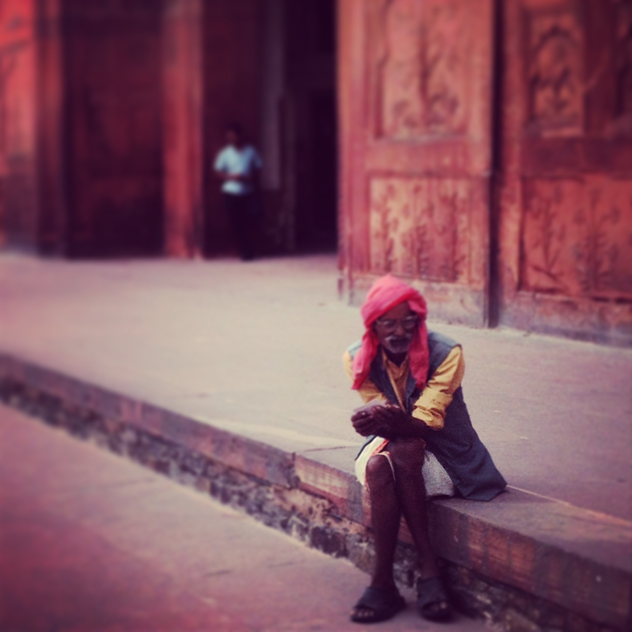 indian man wearing pink turban sitting on a step in delhi