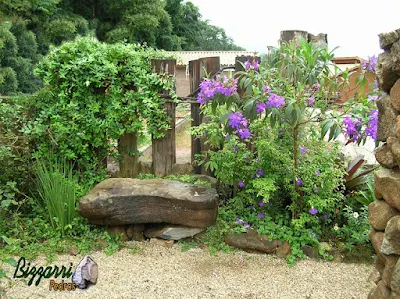 Banco de pedra no jardim, com pedra moledo, com a execução do paisagismo com o piso com pedregulho do rio com a treliça de dormente de madeira.