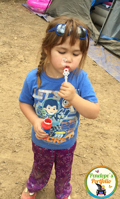A little girl blowing bubbles while camping