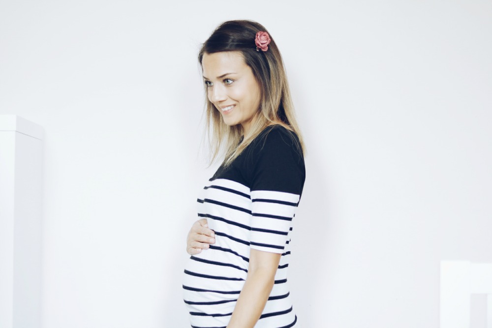 pregnant woman wearing black and white stripy top and pink flower in hair