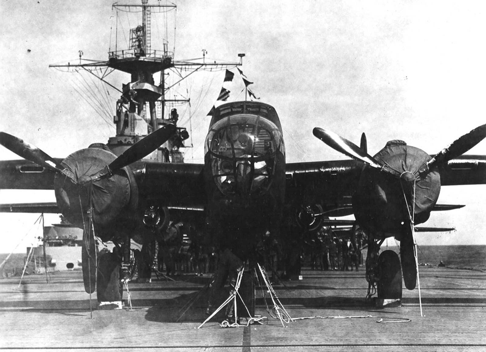 A crew member checks the lashings on his bomber aboard the USS Hornet, while behind him other crews check their planes in preparation for the Doolittle Raid on April 18, 1942.