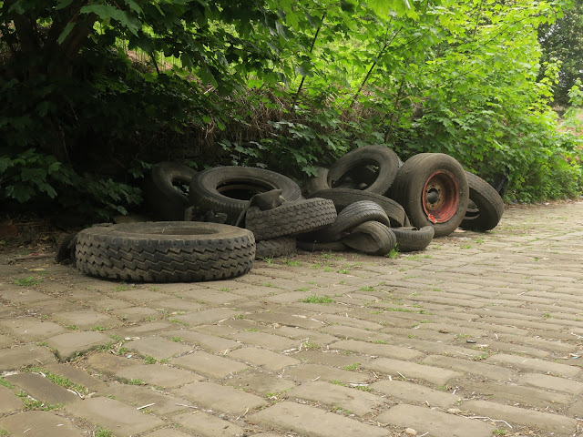 Pile of abandoned tyres on cobbled street.