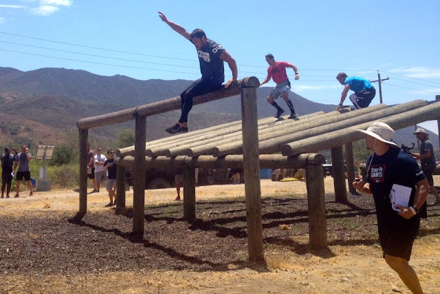 2012 CrossFit Games athletes climbing over an obstacle made of logs in the 12012 CrossFit Games