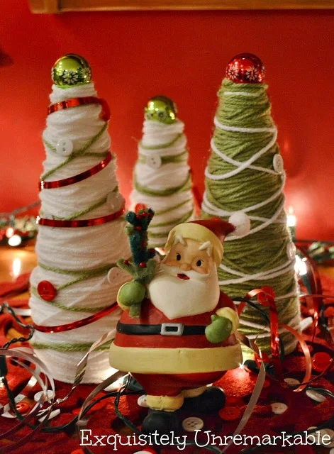 Santa figurine standing in front of Christmas Yarn Trees