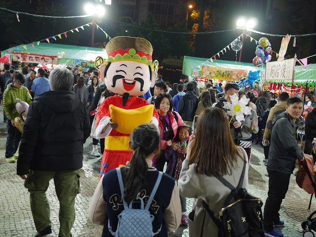 people taking a photograph with person in a God of Wealth costume