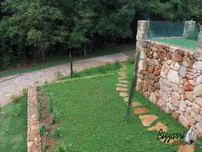 Execução do caminho no jardim com pedra Goiás tipo cacão com juntas de grama com execução do calçamento de pedra com pedra folheta em sítio em Piracaia-SP.