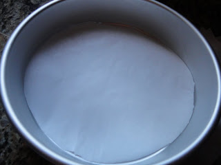 A round piece of parchment paper in a silver colored cake pan.