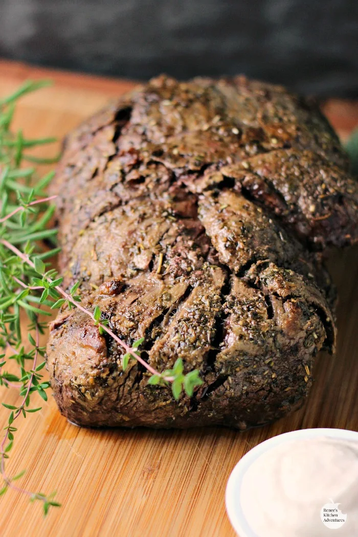 Whole, cooked Garlic Herb Beef Tenderloin Roast with Creamy Horseradish Sauce | by Renee's Kitchen Adventures on cutting board with fresh rosemary garnish