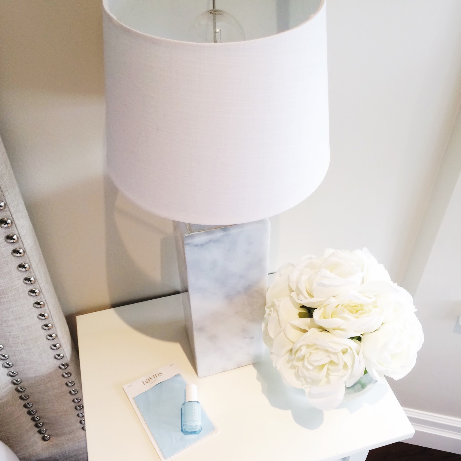 A white lamp on a table with flowers
