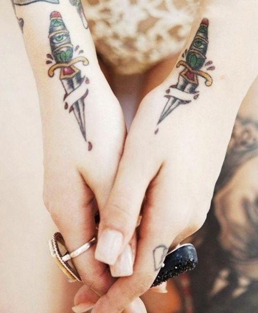manos de una chica que se juntan, lleva en las muñecas tatuajes de dagas
