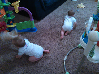 twin babies wearing the onesies playing on the floor