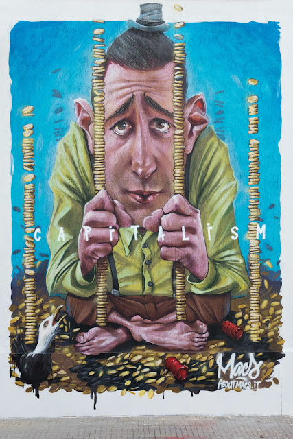 "Capitalism" a poweful new street art mural by Italian artist Macs somewhere in the city of San Vito Chietino in Italy. 2