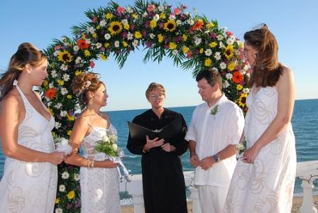 Bridal arch situated on the beach decorated with bright flowers and greenery