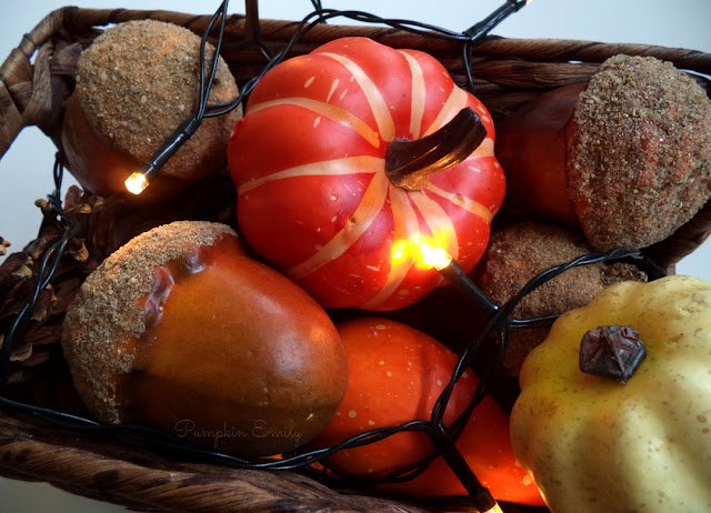 a basket with pumpkins, acorns, pine cones, and a string light in it