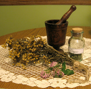 Mortar and pestle with dried herbs and bottle of herbs.
