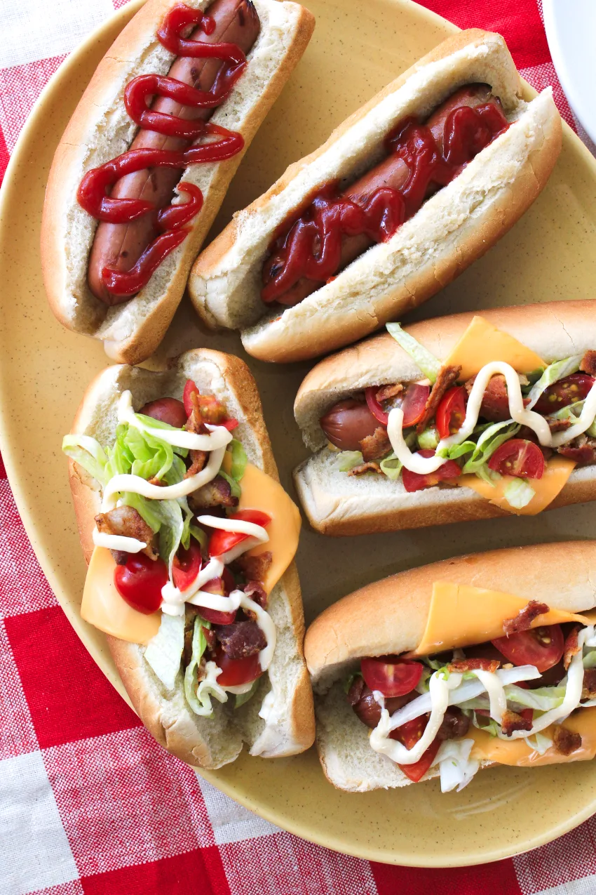 All-American Club Dogs topped with American cheese, lettuce, tomatoes, bacon, and mayo are a fun twist on a summer favorite!  These tasty grilled dogs will be the talk of your next barbecue!  #ad @Kraft @Heinz #hotdogs