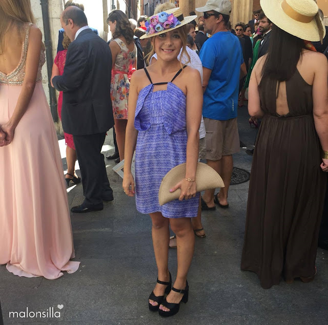 Look invitada boda con vestido corto en azul y malva, canotier de flores de copa baja y bolso abanico 