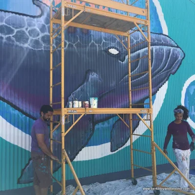 Alise and Jack Eastgate work on their whale mural at Jack London Square in Oakland, California