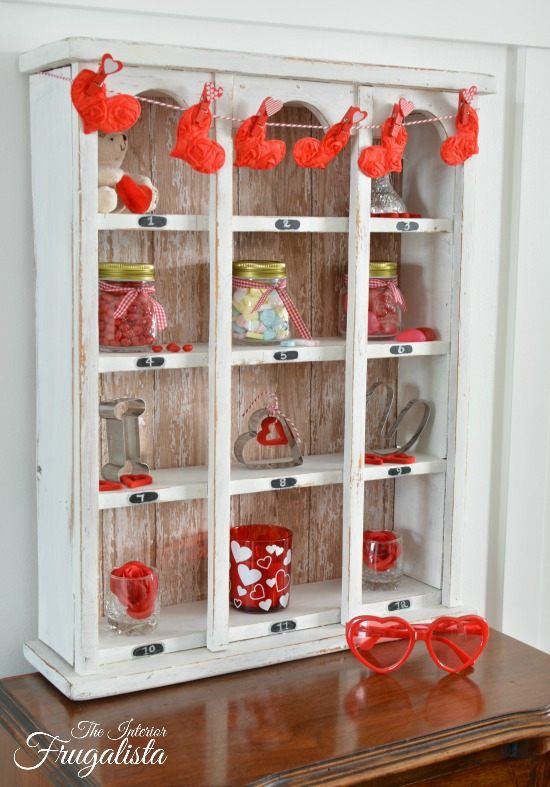 A 12-slot vintage cubby upcycled with barnwood scrapbook paper in farmhouse style and decorated for Valentine's Day with dollar store finds.