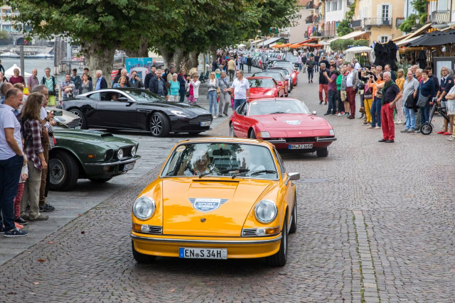 Gelber Porsche 911 Carrera 2.7 RS gefolgt von einem roten Ferrari Daytona, Aston Martin und Mustang. Gelber Porsche 911 Carrera 2.7 RS auf den Sportcars Day 2018 bei der Parade von Ascona ins Maggiatal