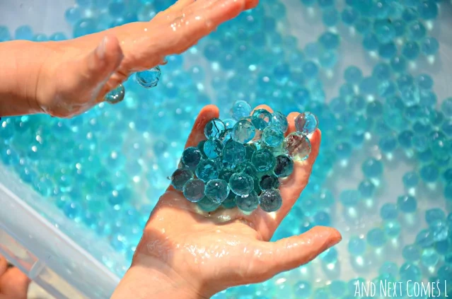 Child holding blue water beads in their hands