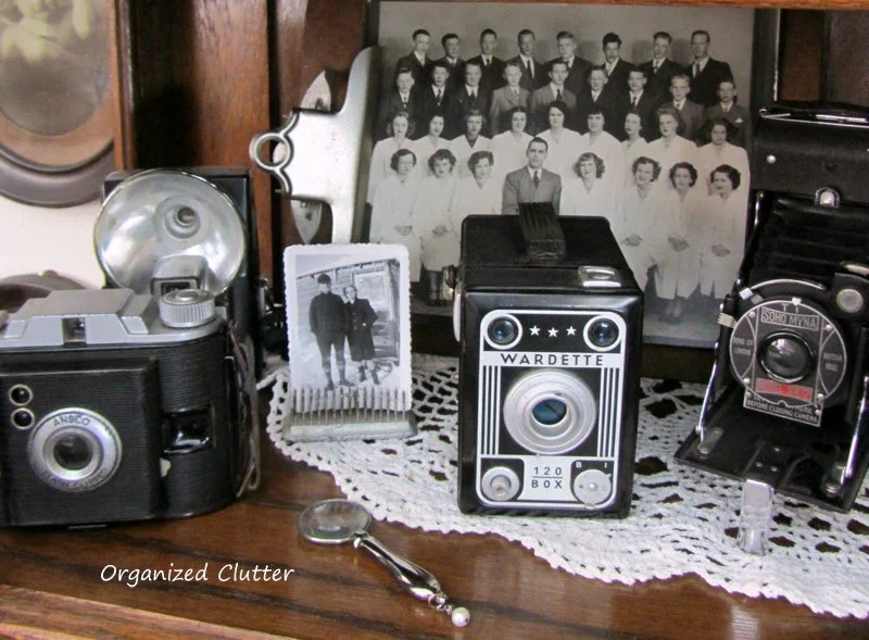 Cameras Displayed in China Cabinet www.organizedclutterqueen.blogspot.com
