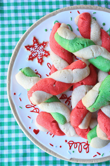 twisted red and green peppermint stick cookies stacked on a holiday cookie tray