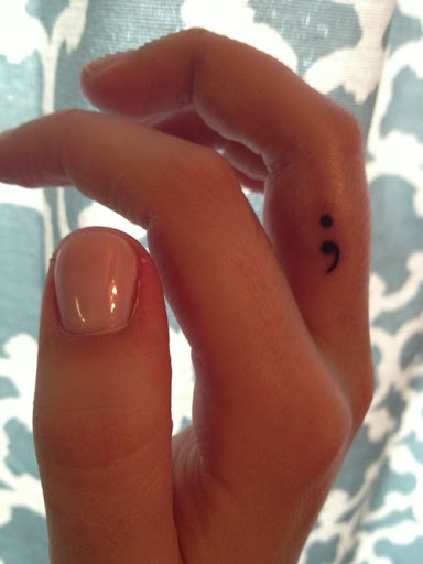 Bonito pequeno ponto-e-vírgula tatuagem no dedo