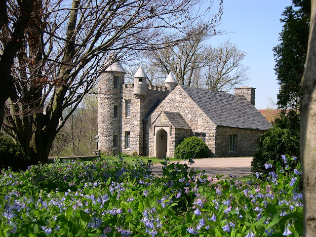 the stone house at yew dell gardens with turrets and the gardens in front with pretty blue flowers in the field